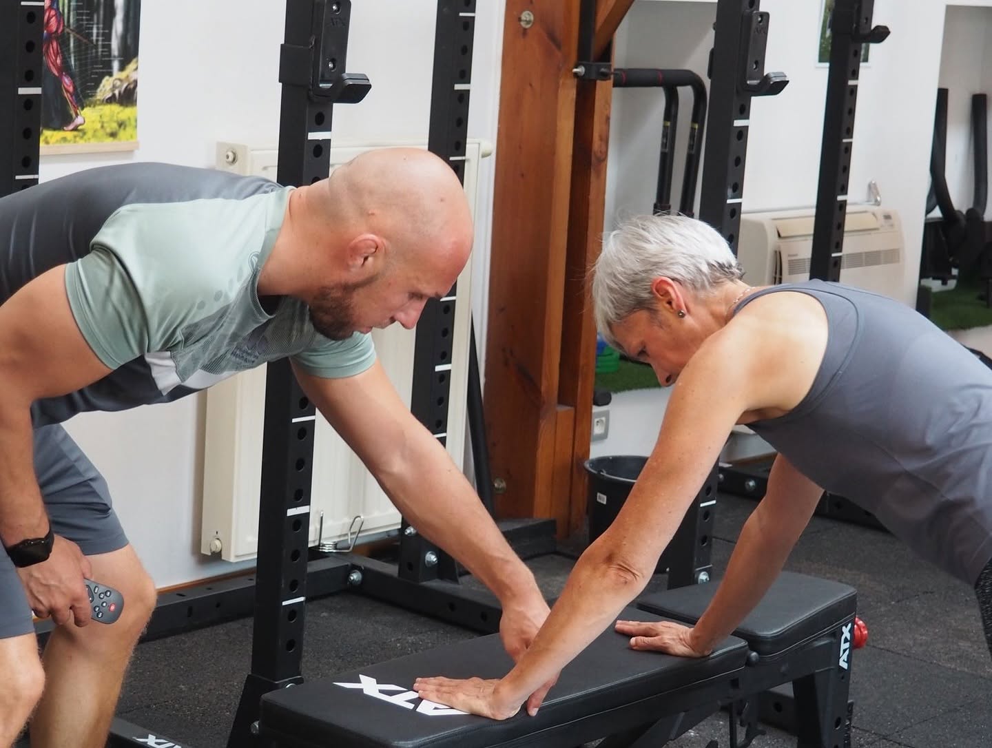 Un coach accompagne une cliente sur un banc de musculation